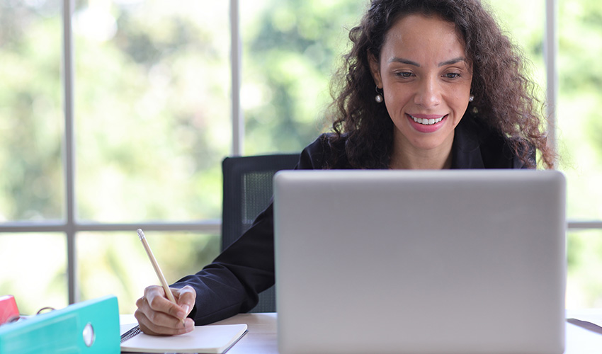 A CSUN student smiles while using her laptop, enjoying her study time and feeling engaged with her work.