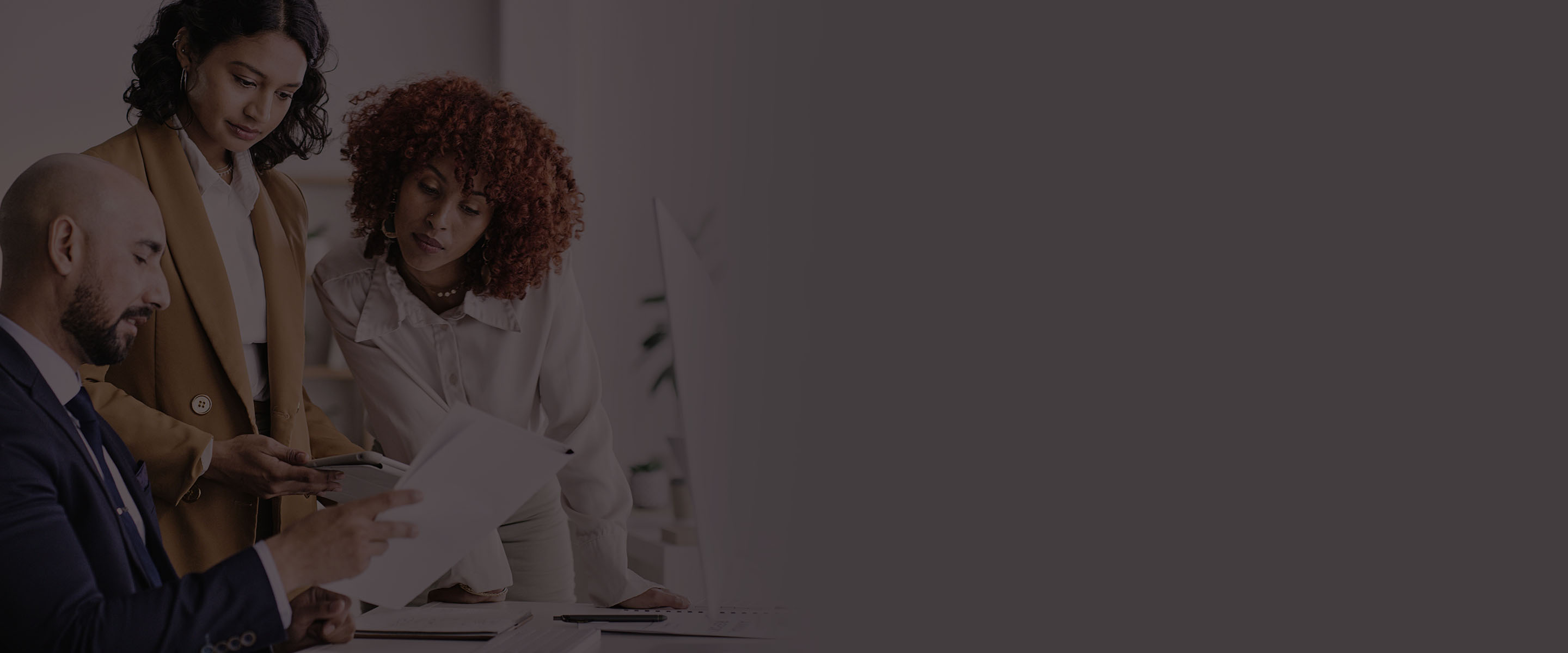 Slider Banner 1 - guy in suit holding documents and two female colleagues standing looking at the documents