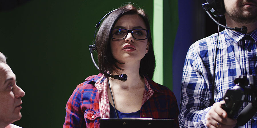 A producer and director standing on the sidelines of a film set.