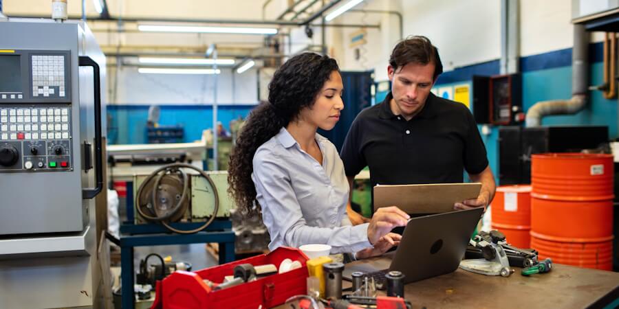 An engineering project manager looking at plans with a team member in an industrial setting.